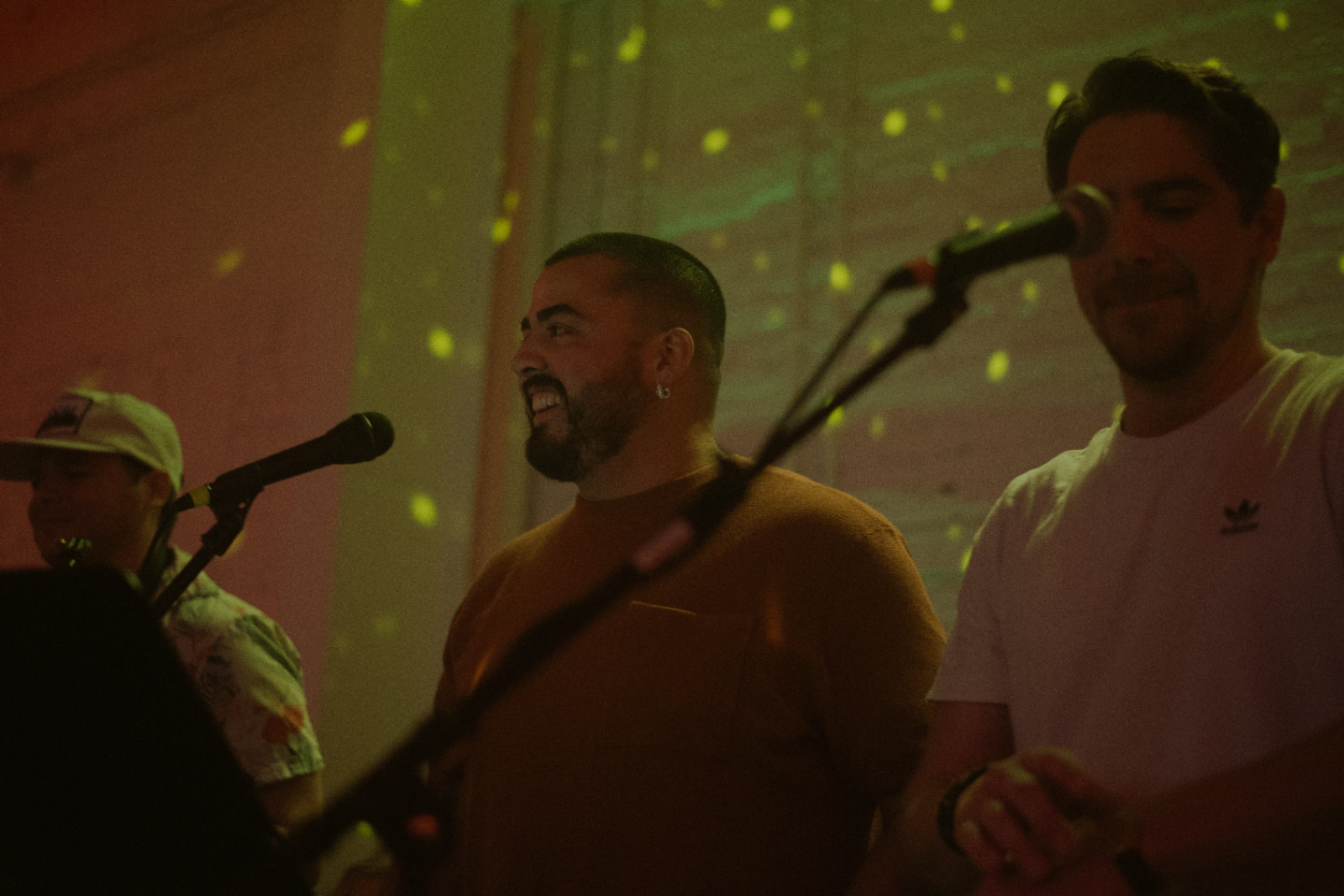 Clayton Munoz singing into the microphone under warm stage light